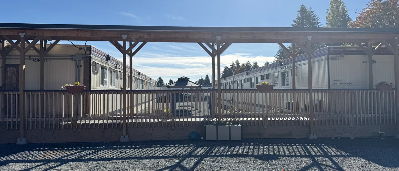 A covered wooden walkway with flower planters at a supportive-housing site in Nanaimo
